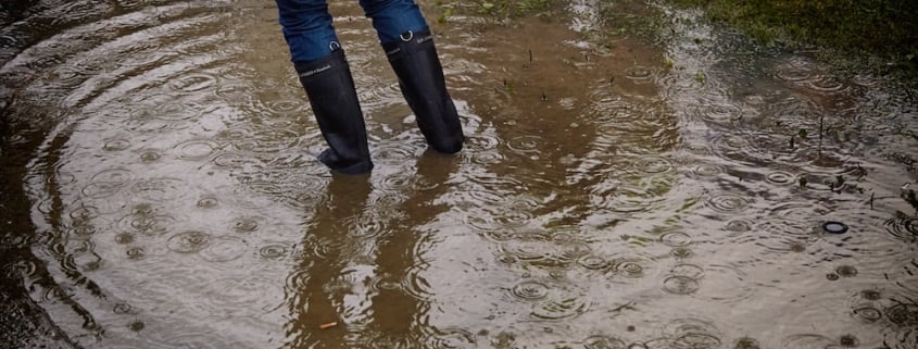 A women standing in a muddy puddle outside a house for sale in Florida.