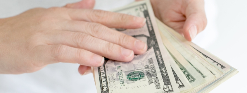 Two hands holding cash from a cash home buyer.